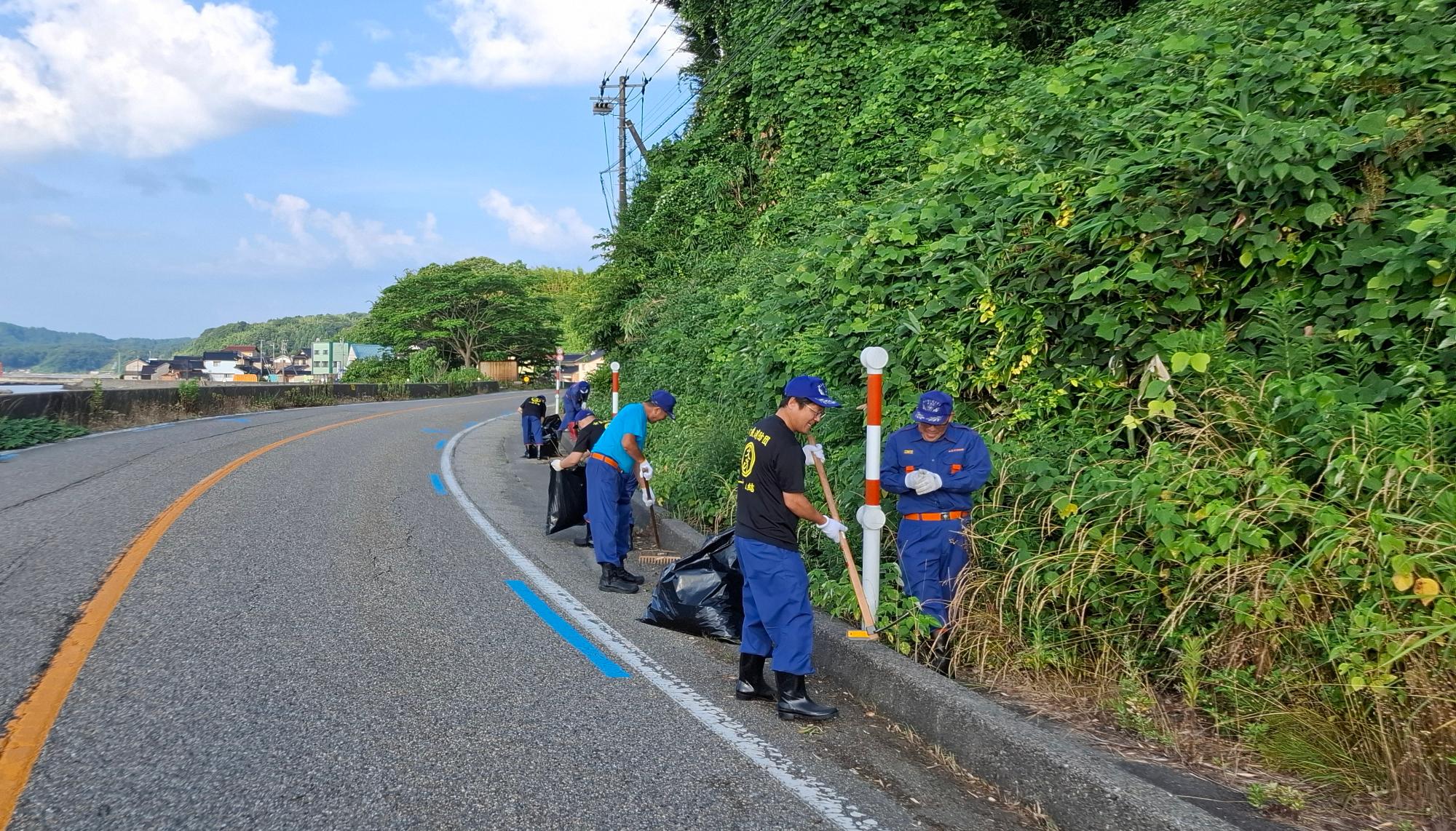 消防団員が歩道の除草清掃活動をしている写真