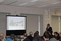 氷見市地域自慢大会の第1部にて多くの人が座っている中で一人の人がスクリーンの映像を使って話している写真