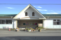 入り口に緑や花が置いてある白い壁の十二町保育園園舎の写真
