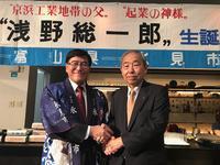 浅野総一郎生誕のパネルの前で浅野様と握手をする市長の写真