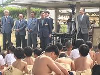 相撲大会の土俵前に市長他5名の関係者が立ちその前に座っているまわしを着けた子どもたちの写真