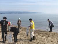 松田江浜の砂浜で6名が袋を片手に持ちゴミを拾っている写真
