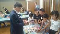 テーブルの上で子供達とツマンコ(くじ引き)遊びをする市長の写真