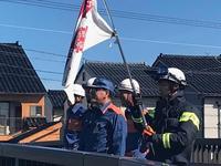 市長の横でヘルメットをかぶった旗を持つ男性とヘルメットをかぶった3名の方々がいる写真