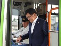 バスの運転手横にある料金箱に手を伸ばしている市長の写真