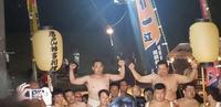 左右の大きな相撲の提灯の間で2人の力士が両腕を上げている写真