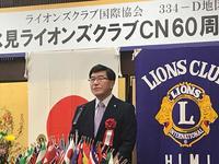 日章旗とライオンズクラブの旗の前の演壇に立つ市長の写真