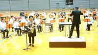 コンサート会場で壇上の指揮者と楽器を演奏する方々の写真