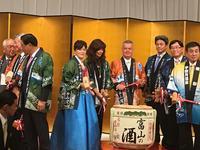 富山産の樽酒の鏡開きを構える総会参加者たちの写真