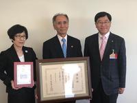 文部科学大臣賞状と表彰盾を持つ二人と並んで撮影された市長の写真