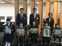 椅子に座り自分の作品をもっている受賞者の生徒男女と市長の写真