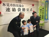 連絡袋贈呈式で2人の新小学1年生と市長が並んだ写真