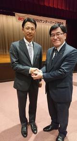 激励会の会場で二岡氏と握手する市長の写真