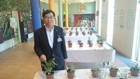展示された鉢植えハーブが数多く並べられたテーブル横に立つ市長の写真
