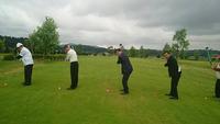 芝生で6人が並び同時にゴルフのスイングをする写真