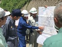 土砂崩れの現地で地図を広げて説明する市長と聞く石井知事ほか関係者数名の写真