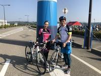 富山湾岸サイクリングに参加する市長とピンク色の服をきた人が青い柱の前にいる写真