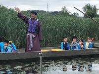「HIMI万葉フェスティバルin布勢水海」にて十二町潟遊覧の舟から立って手をあげている市長と座っている子どもたちの写真