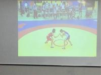 試合マットの上にいるレスリングの選手2人がスクリーンに映し出されている写真