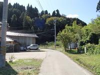 両端に家屋と木々が生えている舗装前の道路の写真