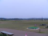 曇り空のもとティーグラウンドとベンチがあるパークゴルフコースの写真