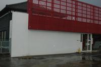 白い壁に赤色のフェンスがある建物の外観の写真