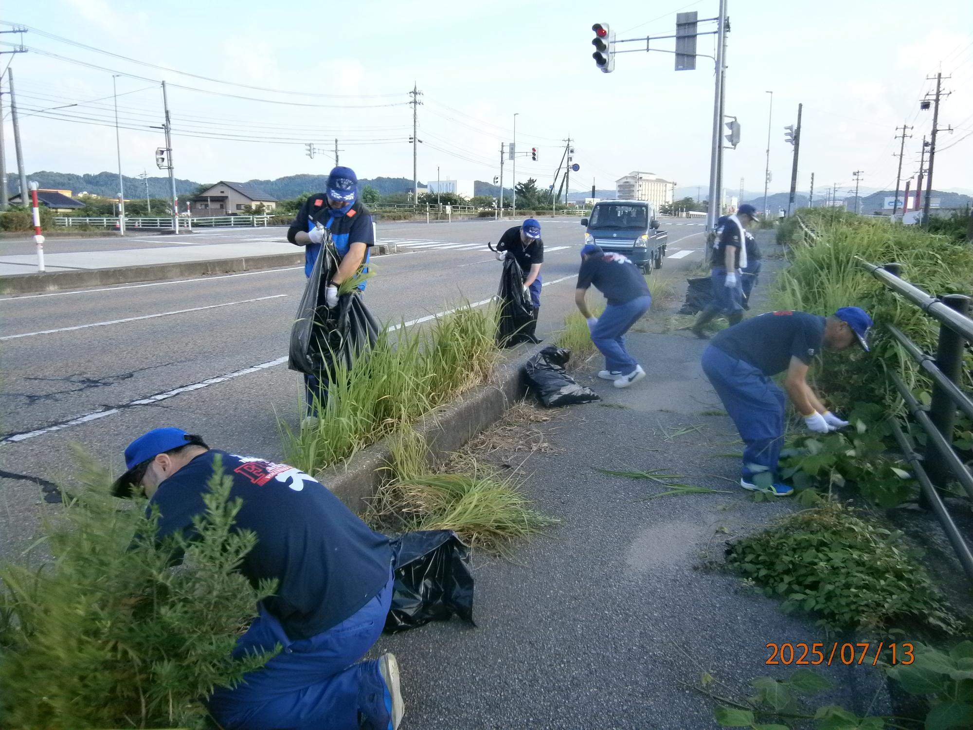 消防団員が歩道の除草清掃活動をしている写真