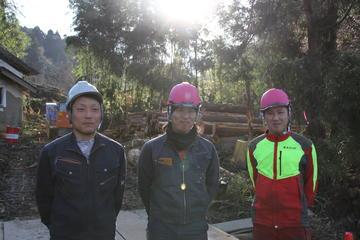 木々に囲まれた場所で3人の男性がヘルメットをかぶって正面を向いている写真